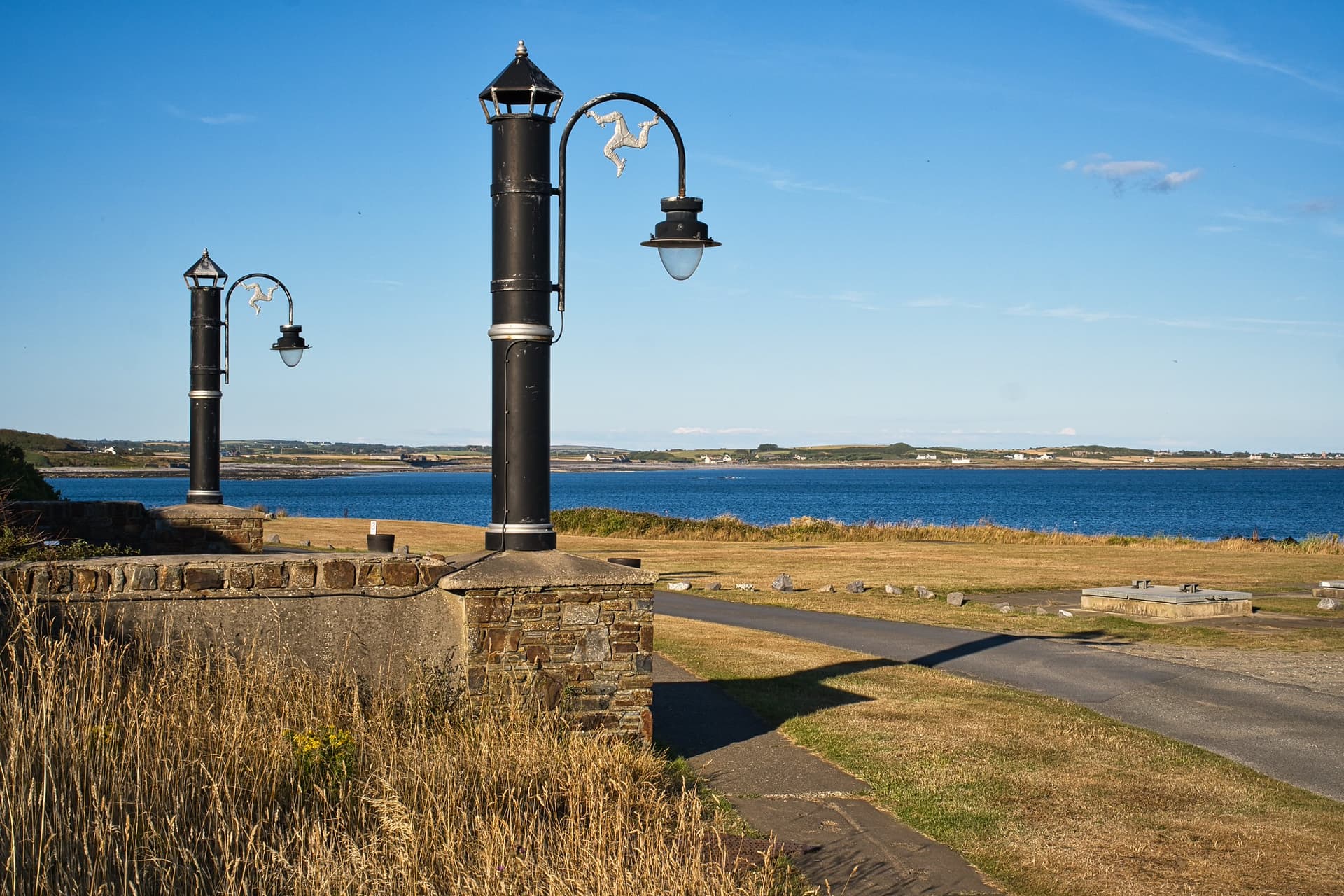 Lampposts with triskelions on the seafront path near Gansey