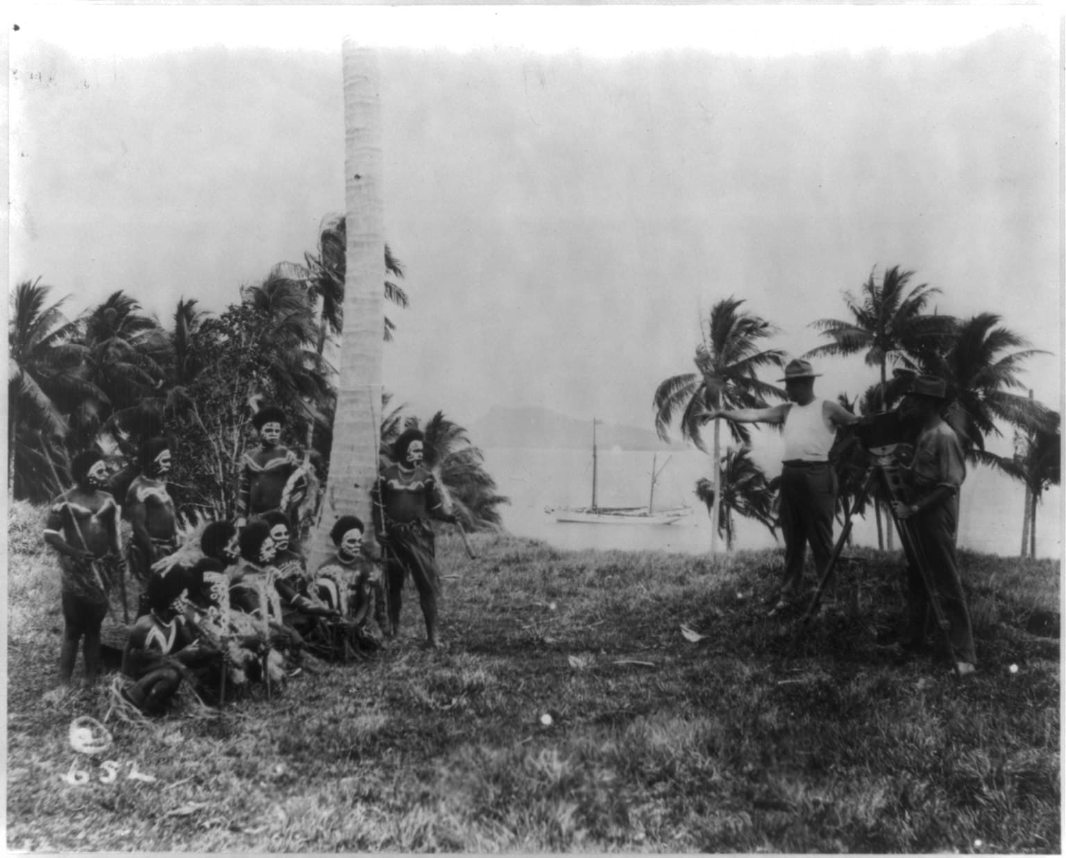 Edward A. Salisbury and his motion picture cameraman "shooting" a group of war-painted Choiseul Island (Solomon Islands) natives holding spears and knives