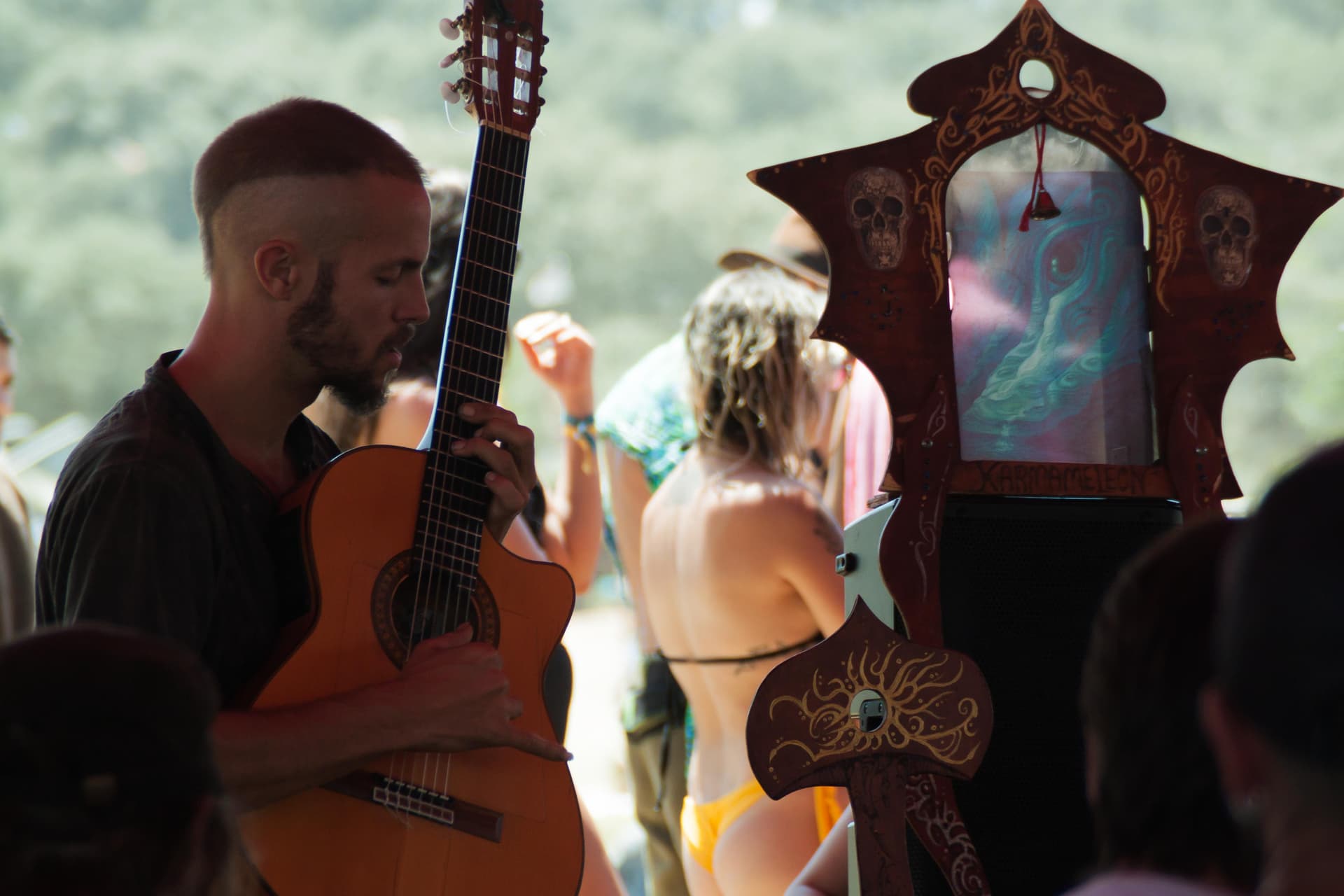 Musician with a guitar beside a painted shrine