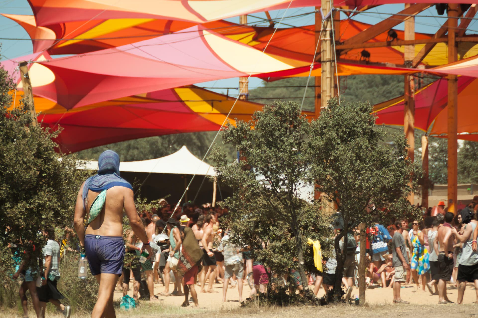 Crowd beneath red and orange shade sails